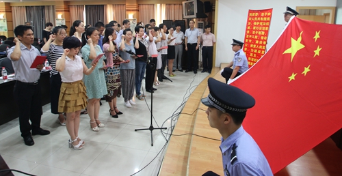 19名新任人民陪审员手持宪法，面对国旗庄严宣誓。.JPG